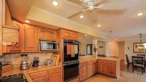 A kitchen with wooden cabinets, a microwave, a stove, and a ceiling fan. - Private 3 Acre Home North Nashville (Goodlettsville)
