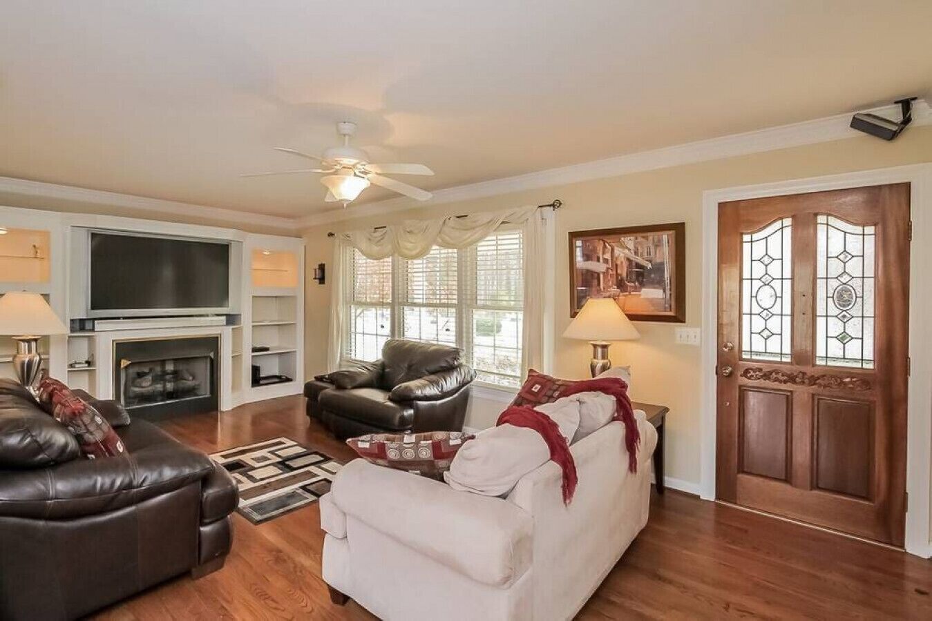 A living room with a fireplace, leather sofas, a coffee table, and a door with stained glass.
