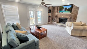 A living room with a fireplace, a ceiling fan, and a television mounted on the wall. - Family Friendly Lake Home, Private Boat Dock, Lake Ozark  (Lake Ozark)