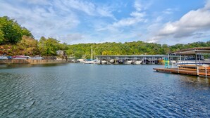 A marina with boats docked, a wooden pier, and a forested hillside in the background. - Family Friendly Lake Home, Private Boat Dock, Lake Ozark  (Lake Ozark)