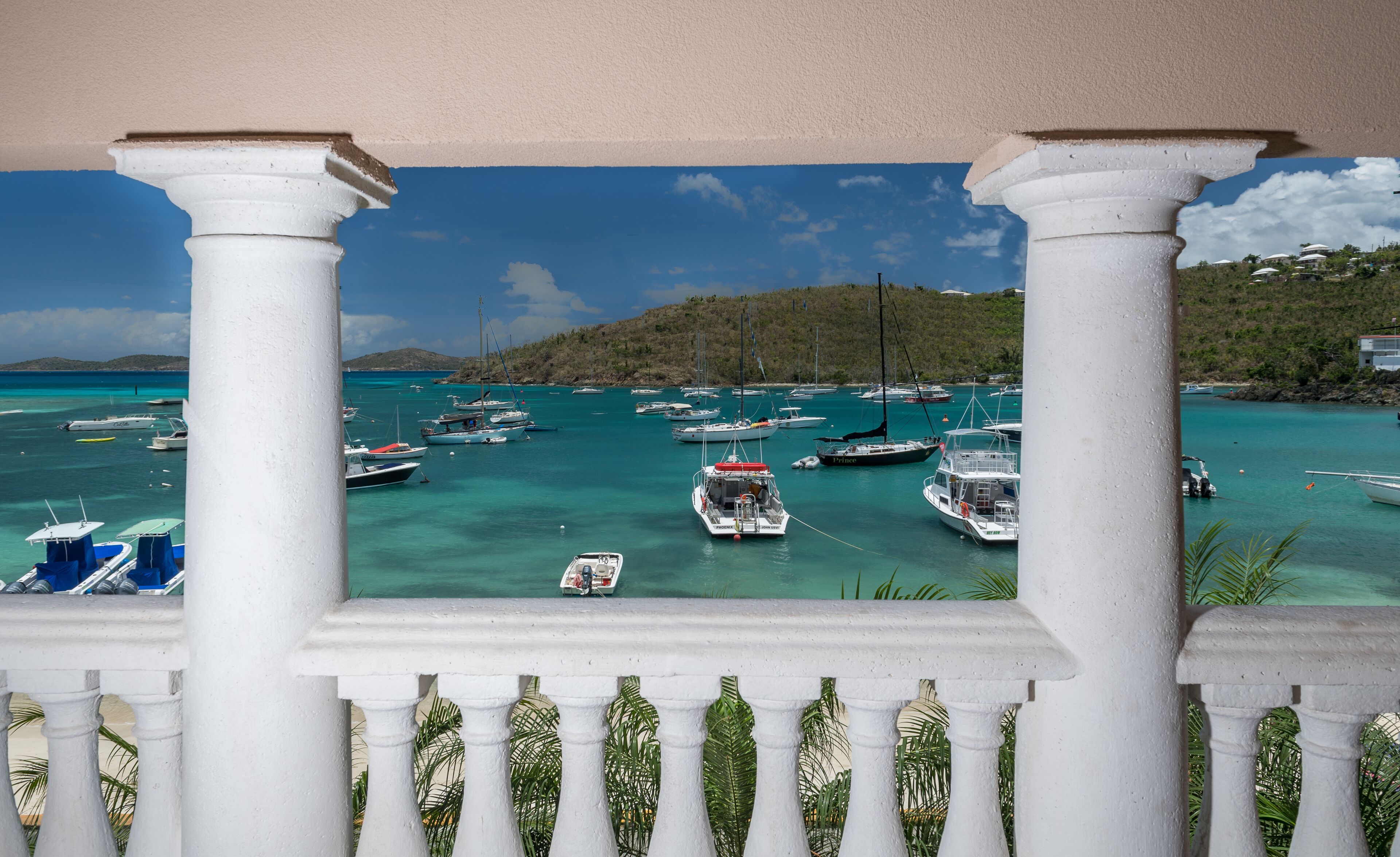 A marina with boats docked, surrounded by greenery and hills.