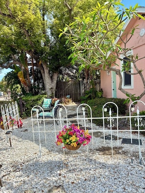 A garden area with a gravel path, metal fence, and a flower pot.