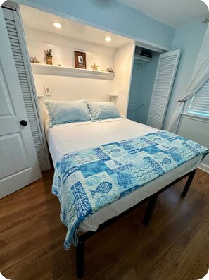 A bedroom with a bed, a bedside table, a nightstand, a window with curtains, and a door. - Walkable Dog Friendly Cottage Downtown (Dunedin)