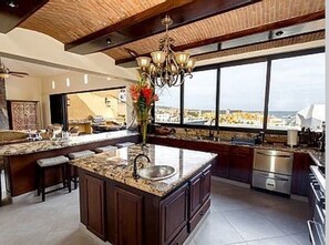 Enjoy cooking in this well-equipped kitchen with a large island, stainless steel sink, and dark cabinets.