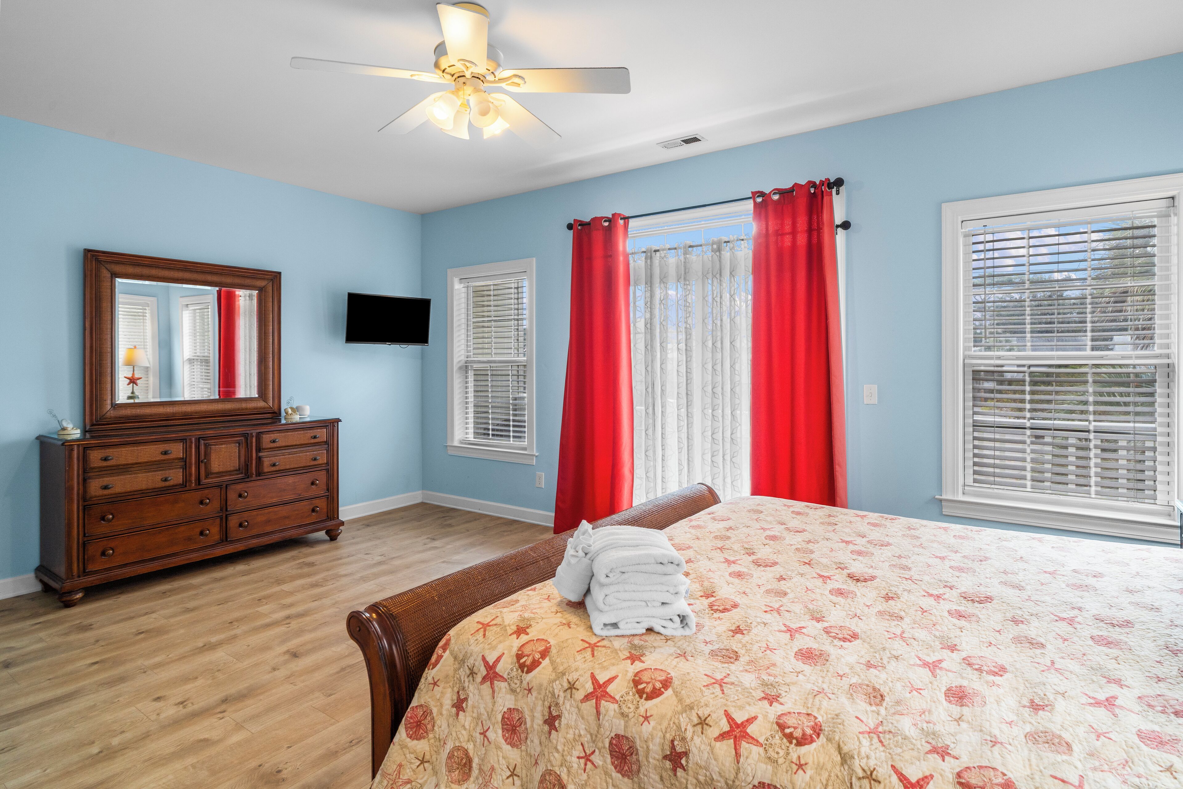 A bedroom with a bed, dresser, and a ceiling fan.