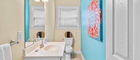 A bathroom with a sink, toilet, and a mirror.