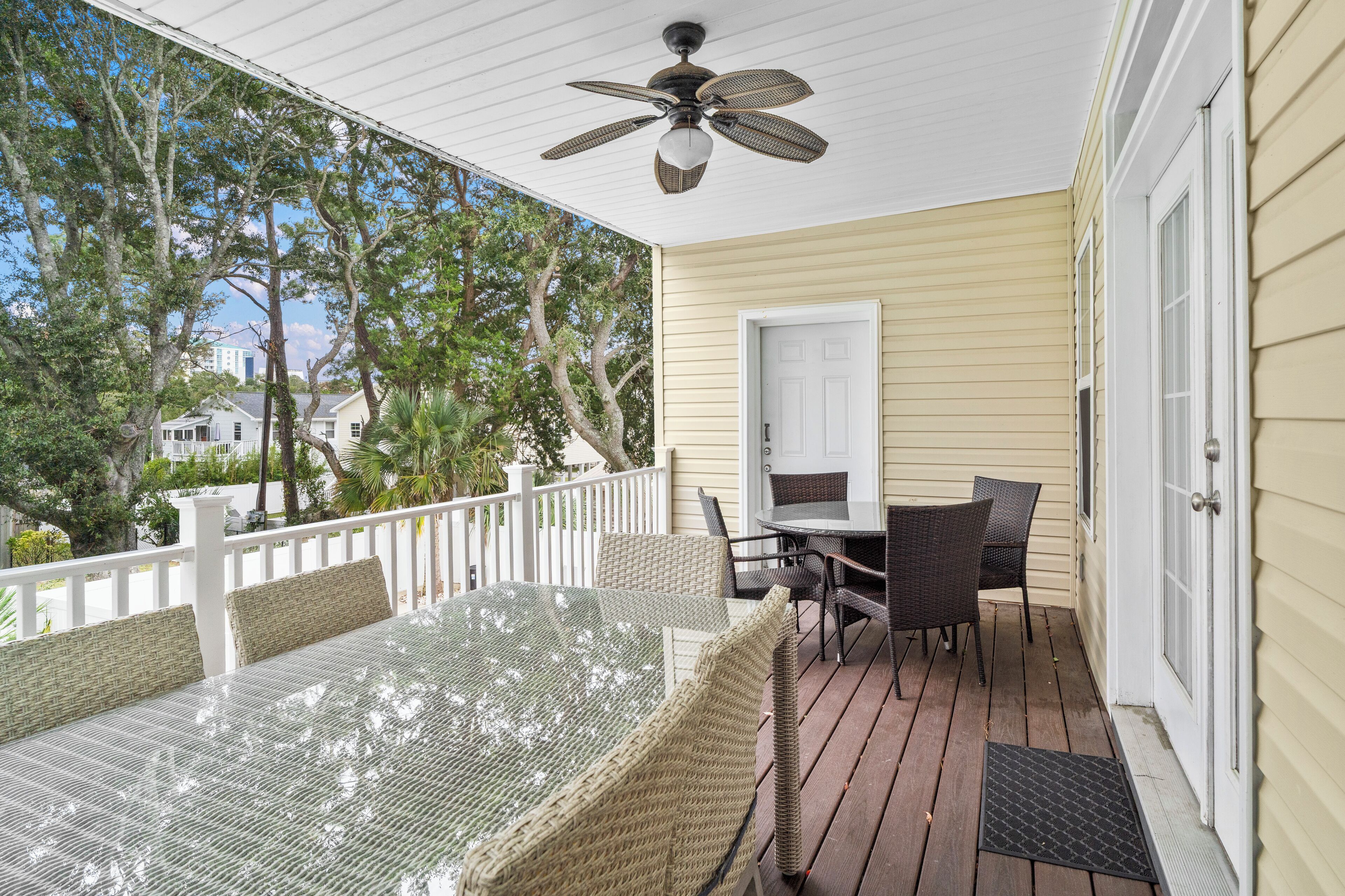 A covered porch with a table and chairs, a ceiling fan, and a door.