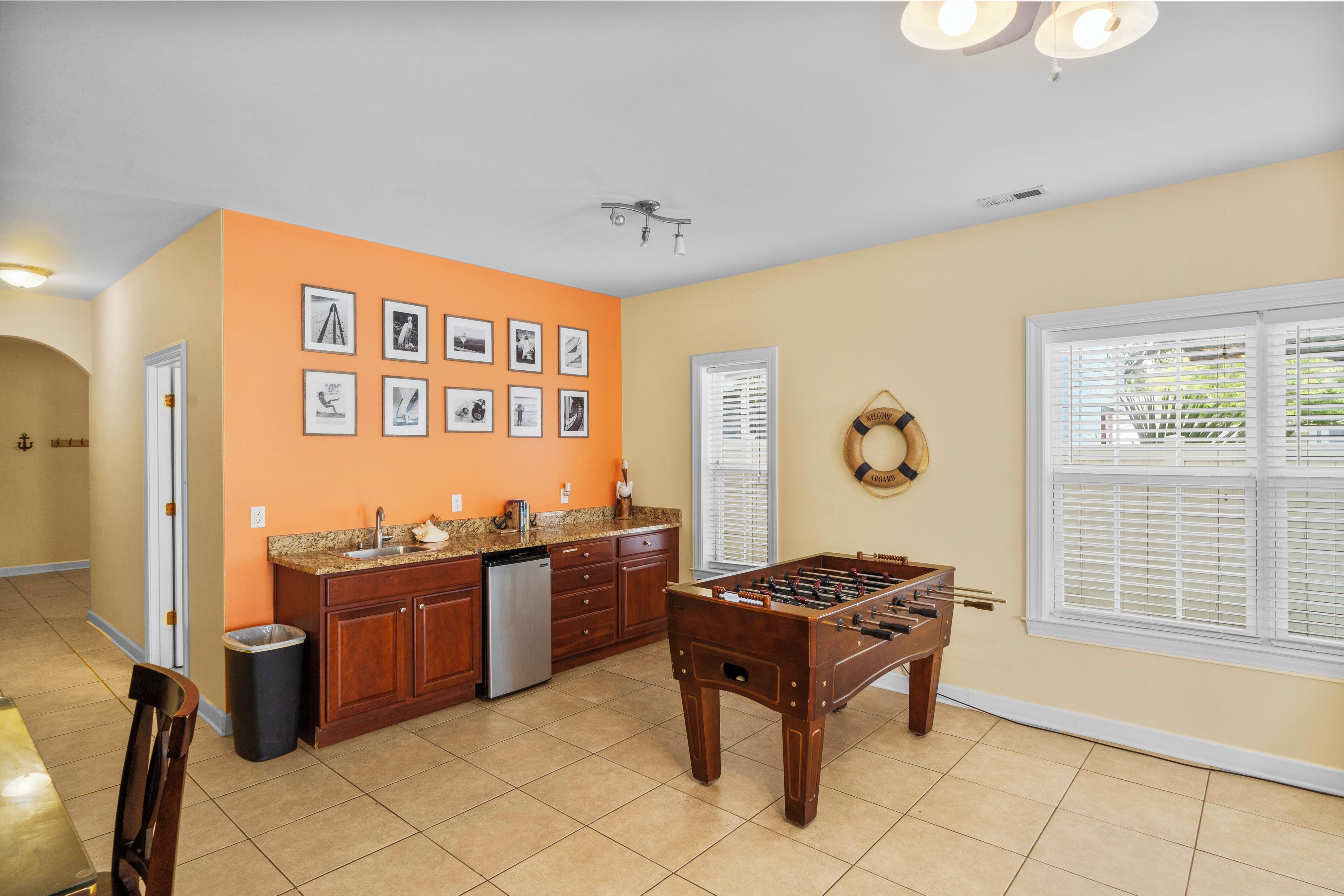 A kitchen with a foosball table, a dishwasher, and a trash can.