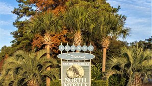Segnale turistico di North Myrtle Beach, Carolina del Sud, immerso nella vegetazione tropicale.