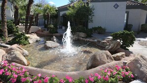 A courtyard with a water fountain, large rocks, and pink flowers. - Luxury Rental in North Scottsdale-2 Bed/2Bath (Scottsdale)