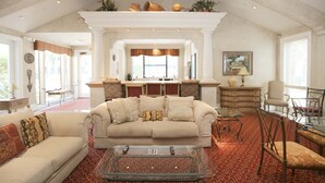 A spacious living room with a high ceiling, a fireplace, a sofa, a coffee table, and a dining area. - Luxury Rental in North Scottsdale-2 Bed/2Bath (Scottsdale)