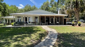 A two-story building with a covered patio area, a paved walkway, and outdoor seating. - Bass Fishing, Kayaking or just Relaxing From Your Own Private Home & Boat Dock  (Dunnellon)