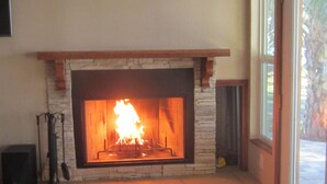 A stone fireplace with a fire burning inside, a window to the right, and a speaker on the left. - Bass Fishing, Kayaking or just Relaxing From Your Own Private Home & Boat Dock  (Dunnellon)