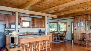 A spacious kitchen with wooden cabinets, a central island with stools, and a dining area with a wooden table and chairs.