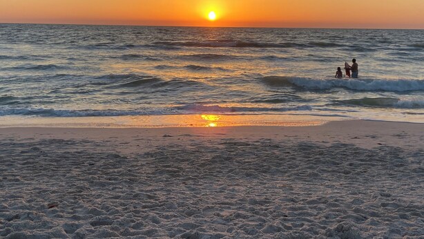 A beach at sunset with waves and a few people in the water. - Peaceful Florida Retreat...Spacious 3BR/3BA Private Pool Home (Bonita Springs)