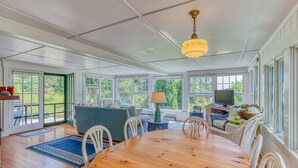 Une pièce spacieuse avec une table à manger en bois, des chaises blanches, un canapé bleu et un téléviseur.