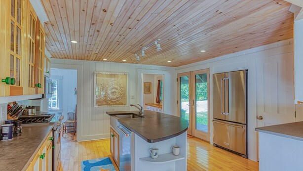 Une cuisine moderne avec un plafond en bois, des appareils électroménagers en acier inoxydable et un îlot central.