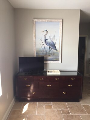 Relax in a serene space with a framed heron painting above a dark entertainment center.