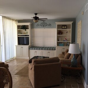 Relax in this spacious living room with a high ceiling, large window, and bench.