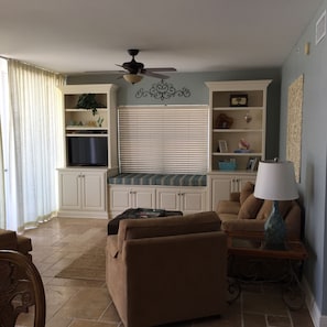Relax in this spacious living room with a high ceiling, large window, and bench.