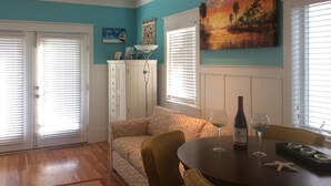 A room with a teal wall, a ceiling fan, a dining table with wine glasses, a sofa, and a painting. - Luxury WATERFRONT condo overlooking pool, 5 mins to Dog Island, FREE boat slip. (Carrabelle)