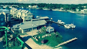 A marina with docked boats, a small dock, and a building with a sloped roof. - Luxury WATERFRONT condo overlooking pool, 5 mins to Dog Island, FREE boat slip. (Carrabelle)