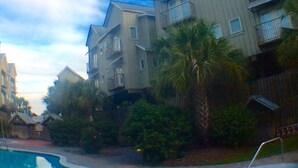 A multi-story hotel with balconies, a swimming pool, and surrounding greenery. - Luxury WATERFRONT condo overlooking pool, 5 mins to Dog Island, FREE boat slip. (Carrabelle)