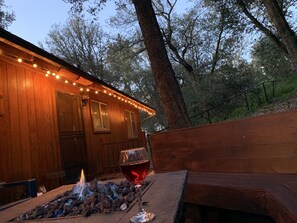 A wooden cabin with string lights, a fire pit, and a glass of red wine on a bench. - Pet &. Family Treehouse style cabin in woods- Full Time Rental as of Oct 1 (Julian)