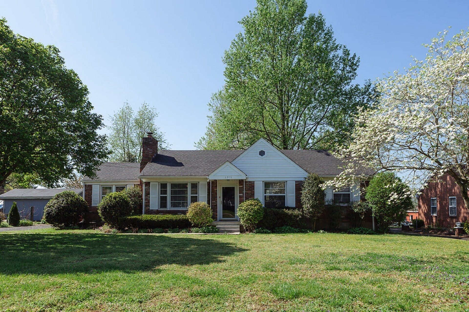 A single-story house with a front porch, a chimney, and a well-maintained lawn.