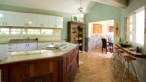 A kitchen with white cabinets, a wooden island, and a bar area with stools.