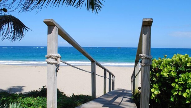A wooden pathway leading to a beach with a clear view of the ocean.
