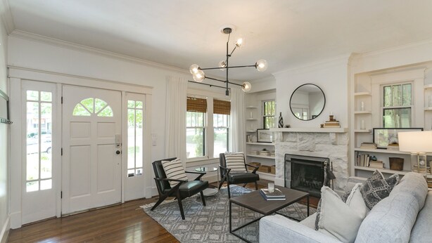 A spacious living room with hardwood floors, a fireplace, and a modern chandelier.