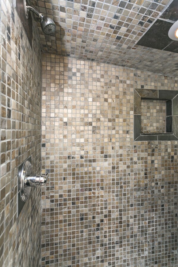 Un baño con paredes de mosaico y zona de ducha.