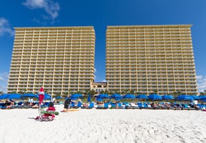 A beachfront hotel with multiple balconies, sun loungers, and umbrellas. - Calypso 2nd Floor Paradise- VIP parking- Daily Beach Chairs - Tower 1 Oceanfront (Panama City Beach)