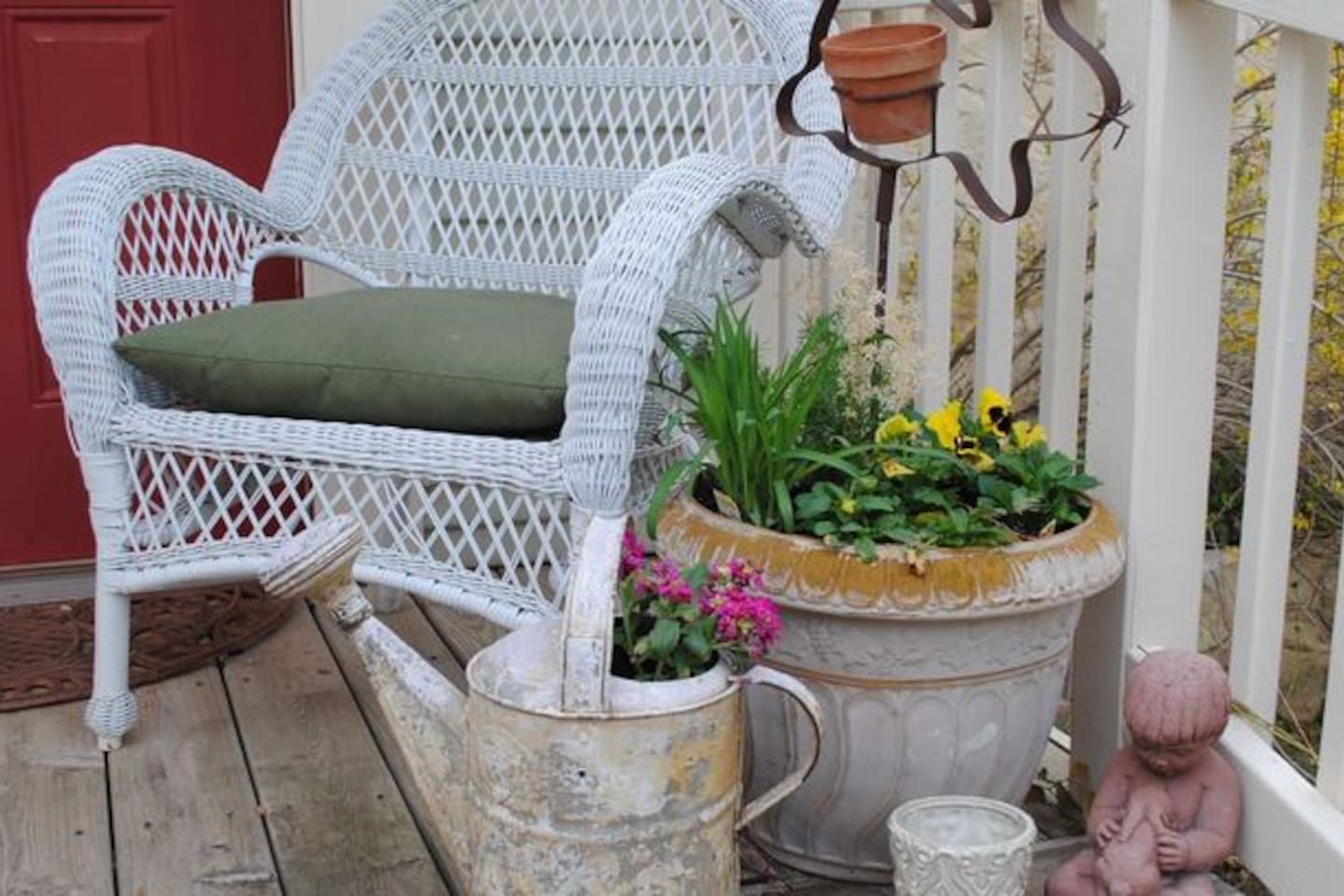 En fletstol med pude, en stor plantekasse med blomster og en lille figur på en træterrasse.