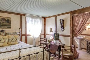 A bedroom with a bed, a desk, a chair, a clock, and a window with curtains.