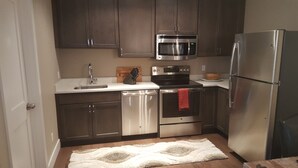 A modern kitchen with stainless steel appliances, dark wooden cabinets, and a white countertop. - Top Floor Timbers Condo in Mt. Crested Butte (Crested Butte)
