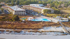 A resort with multiple buildings, a large swimming pool, and a beach area. - Ocean Front 1st Row ~ Private Corner Unit ~ Close to Pool, Beach Bar & Boardwalk (Hilton Head Island)
