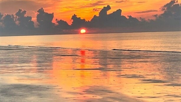 A sunset over a calm sea with a clear sky and distant land silhouettes. - Ocean Front 1st Row ~ Private Corner Unit ~ Close to Pool, Beach Bar & Boardwalk (Hilton Head Island)