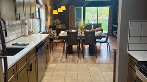 A modern kitchen with wooden cabinets, a dining area with a table and chairs, and a view of greenery outside. - Top-Floor Branson Condo w/ Stunning Views & 2 King Beds (Branson)