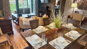 A dining area with a wooden table set for four, surrounded by chairs. There is a large window providing a view of the outdoors. - Top-Floor Branson Condo w/ Stunning Views & 2 King Beds (Branson)