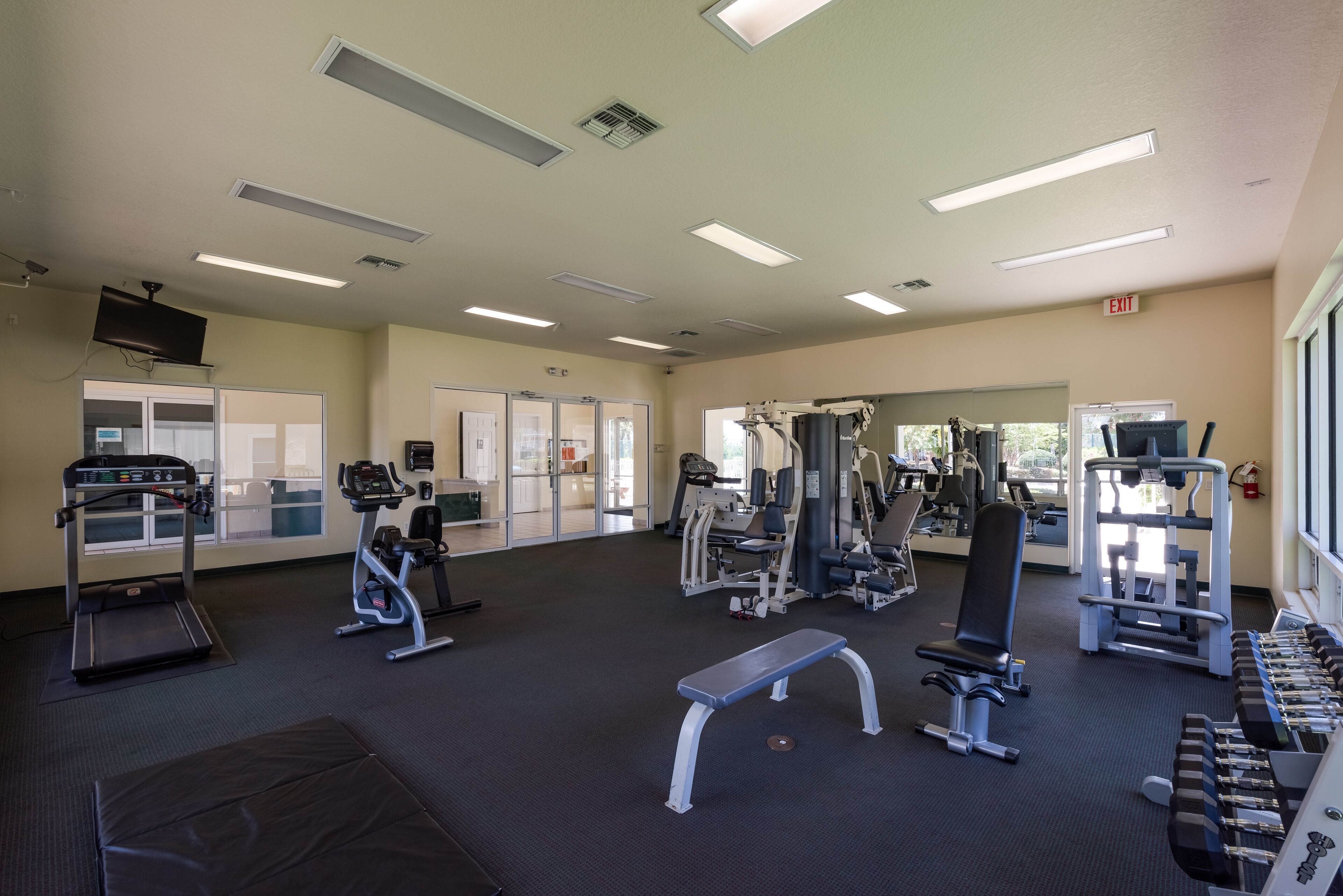A gym with exercise equipment, a treadmill, and a bench.