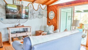 A cozy living room with a television, a sofa, and a wicker coffee table. - WELCOME TO  A PARADISE GETAWAY IN WEEKI WACHEE FLORIDA (Spring Hill)