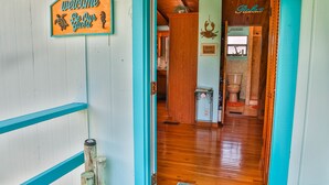 A wooden door with a welcome sign, a wooden floor, and a small bathroom visible through the doorway. - WELCOME TO  A PARADISE GETAWAY IN WEEKI WACHEE FLORIDA (Spring Hill)