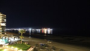 Un hotel sulla spiaggia con piscina, ombrelloni e vista sull'oceano.