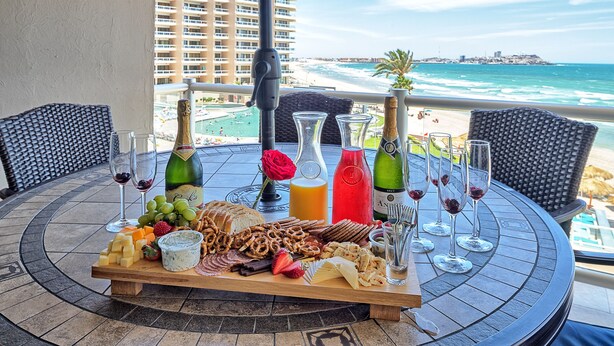 Un tavolo con cibi e bevande assortite, affacciato su una spiaggia e l'edificio di un hotel.