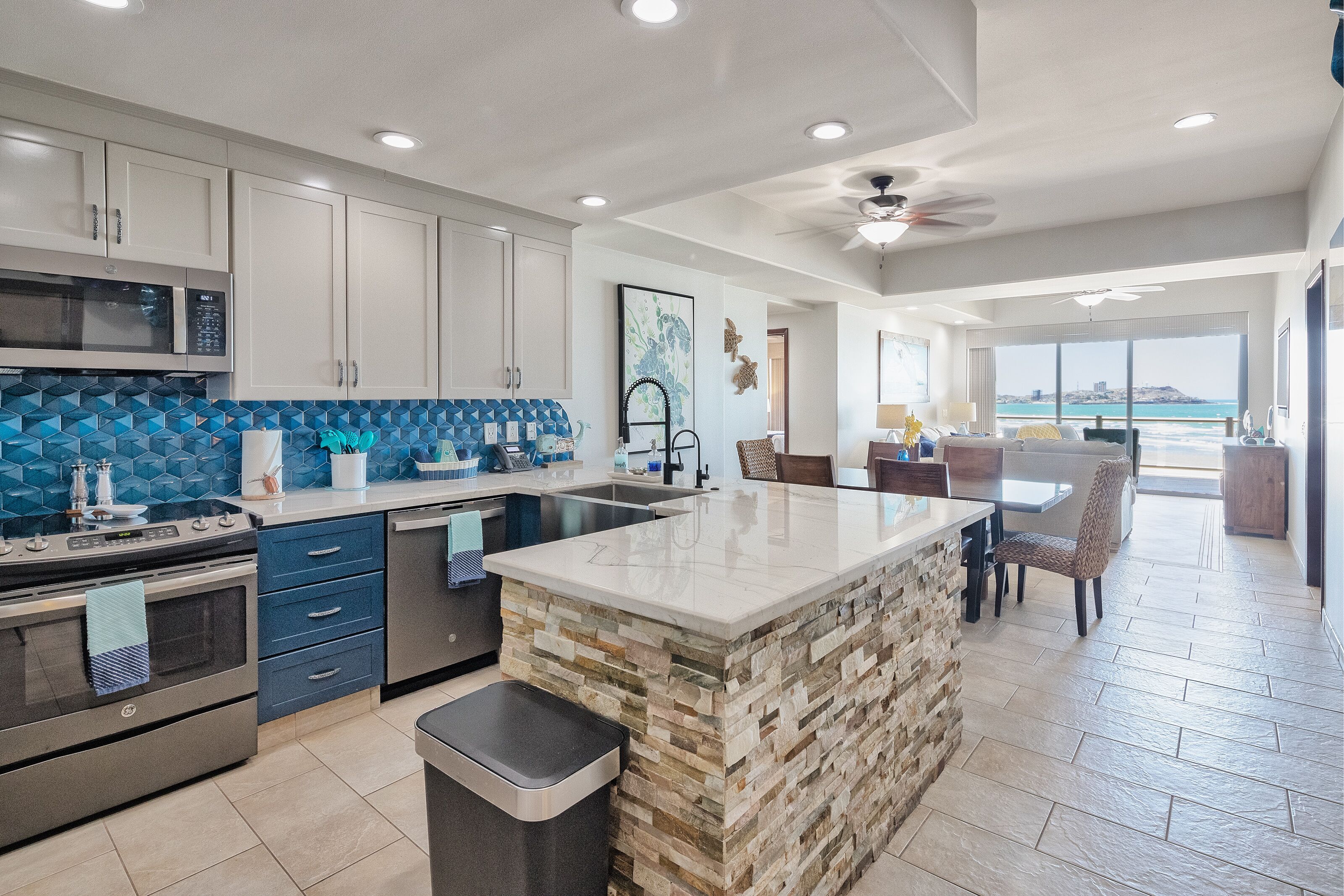 A modern kitchen with a central island, built-in appliances, and a view to the outside.