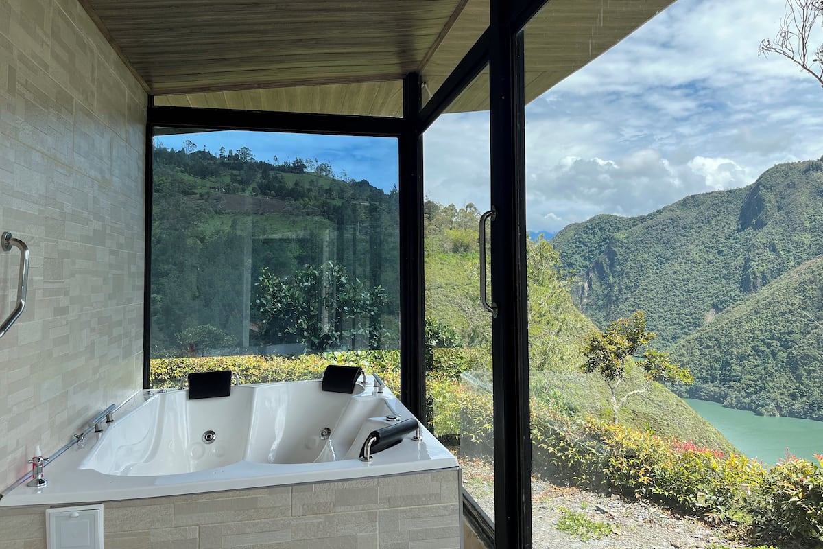 A modern bathroom with a large bathtub and a view of a mountainous landscape.