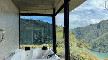 A modern bathroom with a large bathtub and a view of a mountainous landscape.