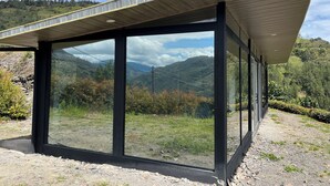 A modern structure with large glass windows offering expansive views of a mountainous landscape.